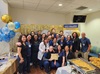 the medical intensive care unit team celebrates their gold level beacon award, which one person is holding, in a conference room with balloons, streamers and food