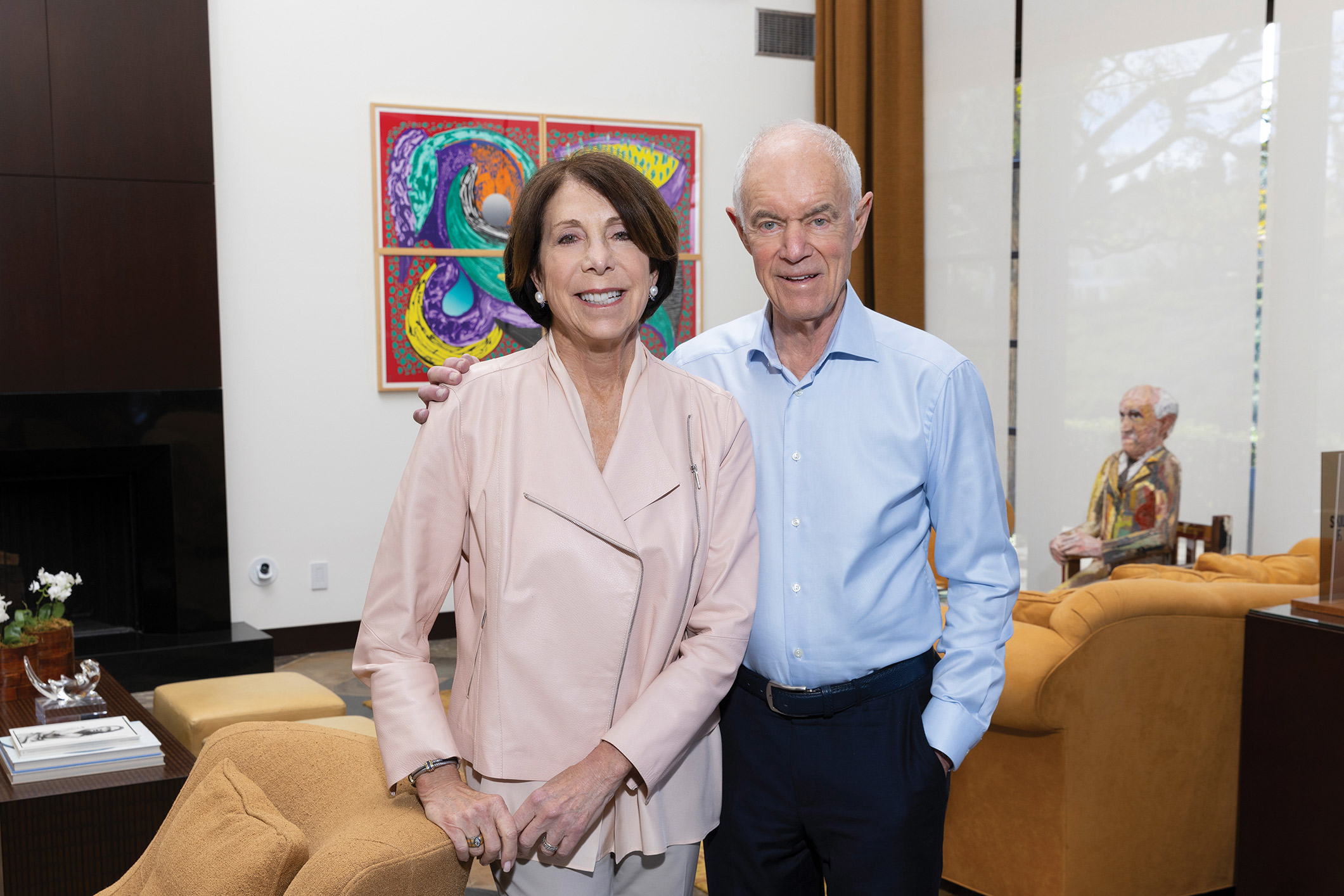 Sue and Ralph Stern stand in a room with a colorful painting in the background.