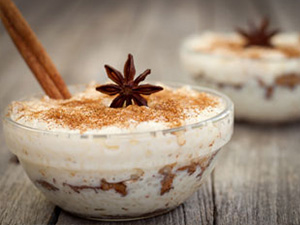 Gingered brown rice pudding is served in a clear bowl with star anise and cinnamon stick.