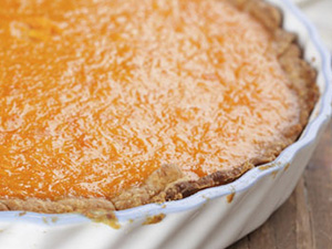 Delicious low-calorie pumpkin pie shines a bright orange in a white ceramic pie dish.