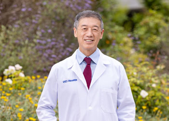 uci health chao family comprehensive cancer center integrative oncologist dr gary deng outside in front of plants wearing a white coat
