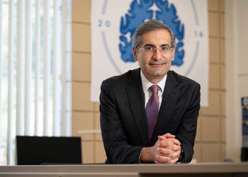 S. Ahmad Sajjadi, M.D., Ph.D., associate professor of neurology in the UC Irvine School of Medicine wears a suit and leans over a desk with his hands clasped