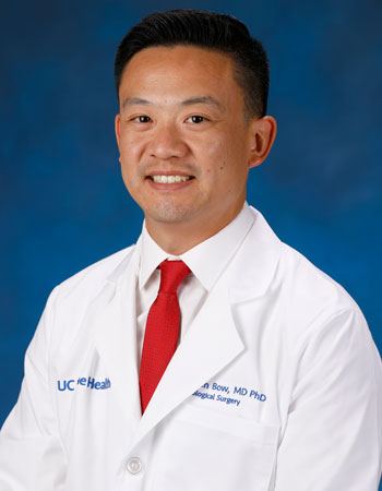 uci health neurosurgeon dr hansen bow wearing a white coat in front of a blue studio background