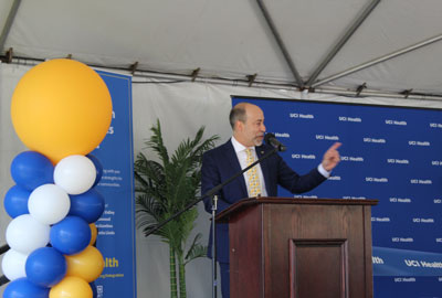 uci health president and ceo chad lefteris addresses the crowd from a podium on stage with balloons at a celebration event after the health system acquired four community hospitals and established the UCI Health Community Network