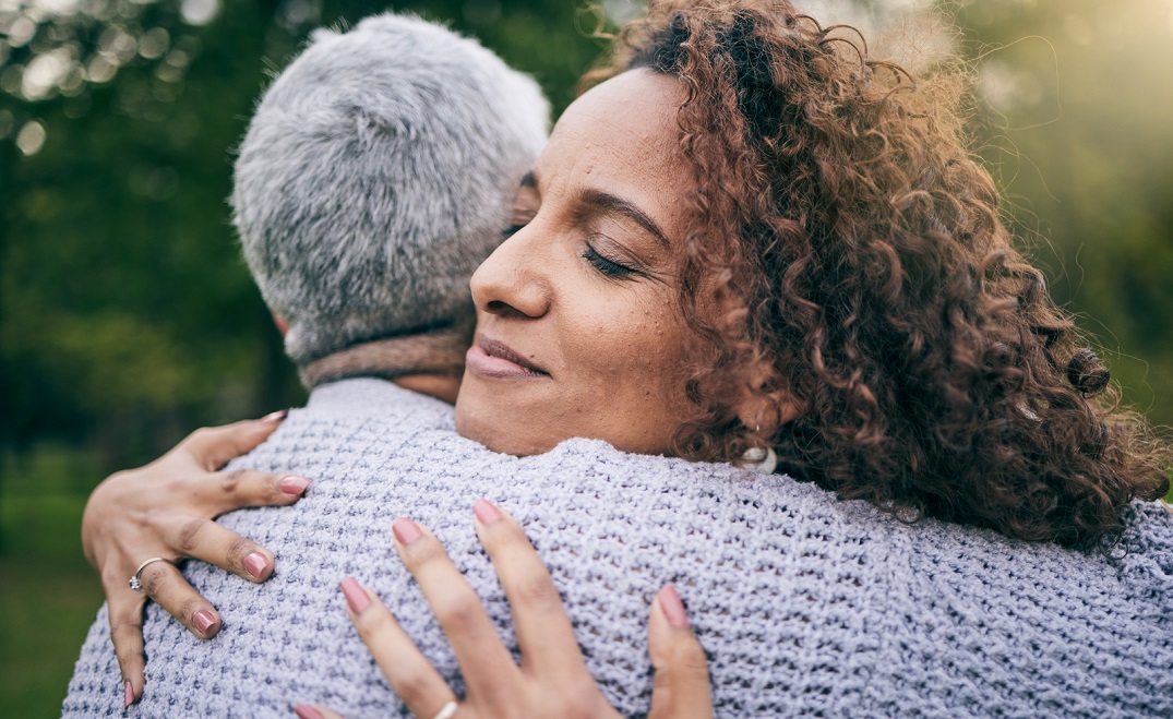 Adult daughter hugs senior mom in closeup image
