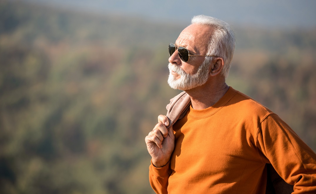 A senior man in sunglasses enjoys the view of nature